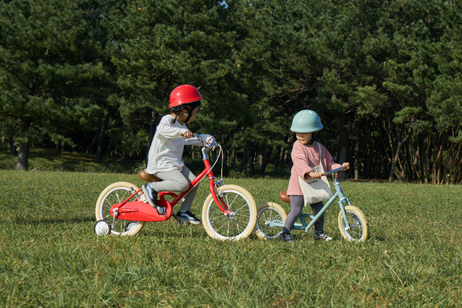 おしゃれなキックバイクと補助輪付き自転車に乗る子供